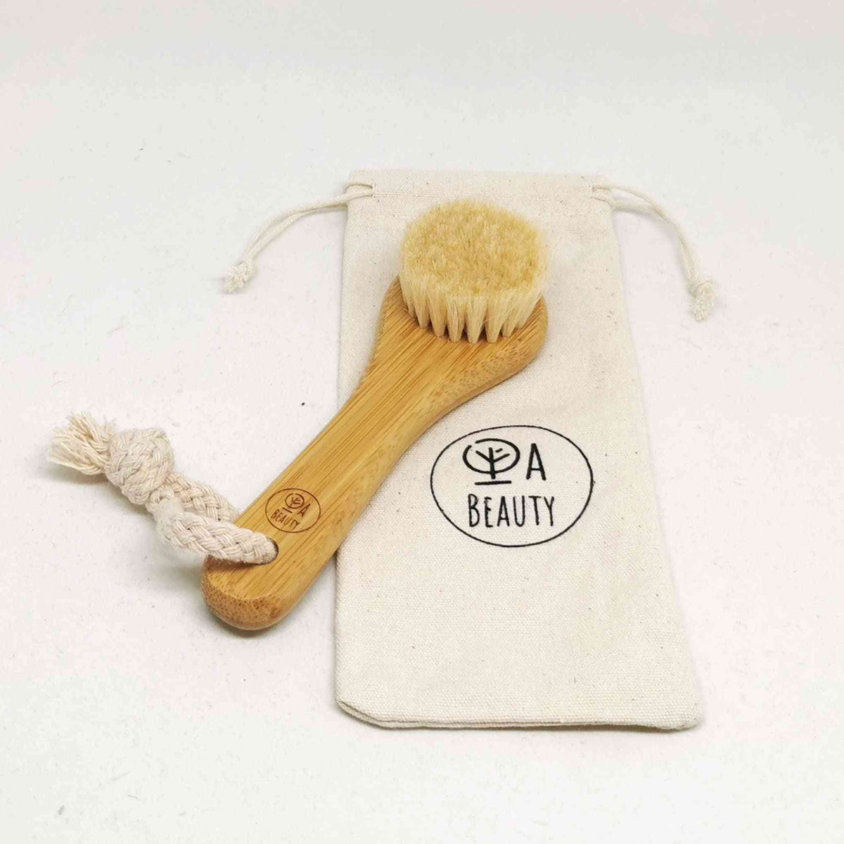 Soft Detox & Glow Face Brush with bamboo handle and goat bristles, displayed alongside a branded cotton storage pouch.
